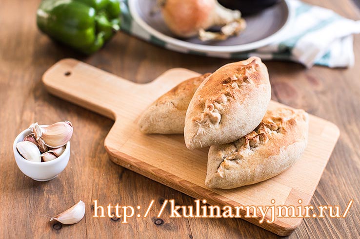 Hot pies with mushrooms on cutting board, vegetable calzone